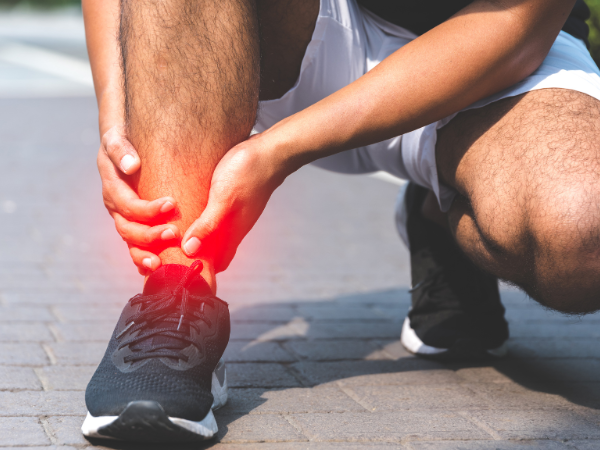 Person hat Schmerzen im Sprunggelenk.