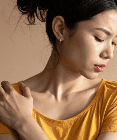 Frau hat an der Schulter Schmerzen.